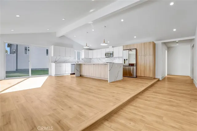 a large space with kitchen view and a refrigerator