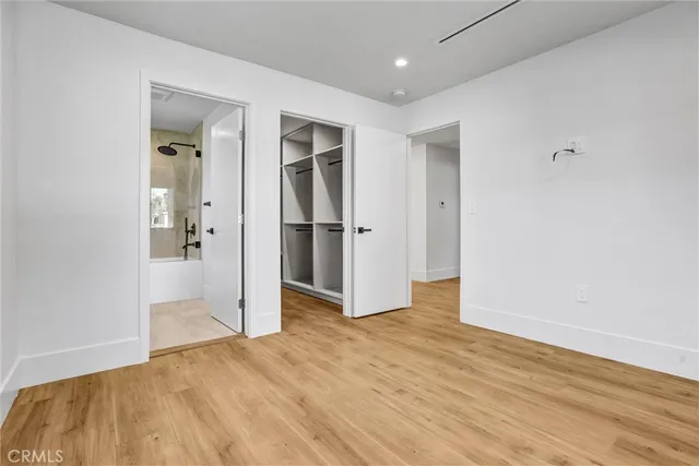 a view of an empty room with wooden floor and a bathroom