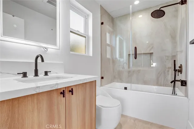 a bathroom with a granite countertop sink mirror toilet and bathtub