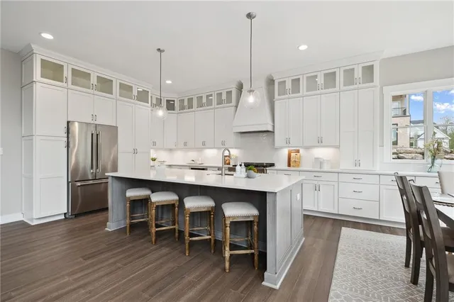 a kitchen with kitchen island granite countertop a stove a sink a dining table and chairs with wooden floor