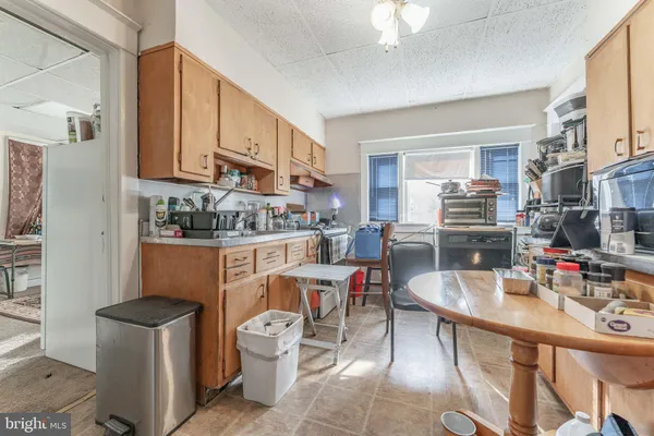 a room with stainless steel appliances kitchen island granite countertop a table chairs in it and a window