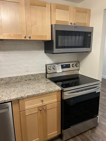 a kitchen with granite countertop a stove and a microwave