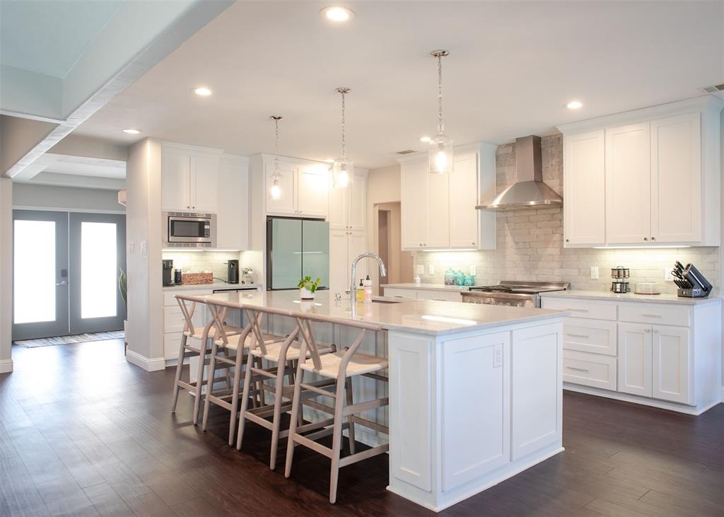a large kitchen with kitchen island granite countertop lots of white cabinets appliances and furniture