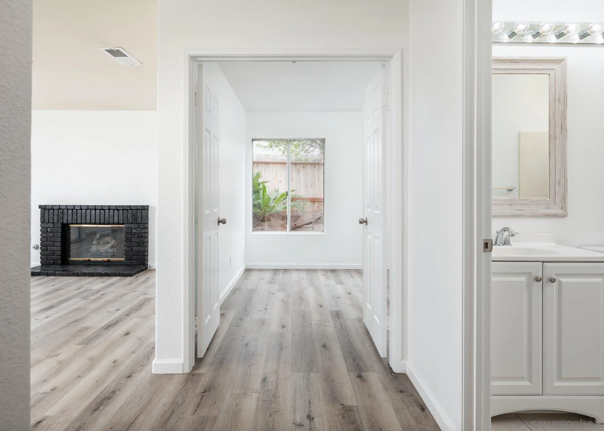 665 Montage Road Oceanside, CA 92057 - Photo 23 of 52 a view of a hallway with wooden floor and a fireplace