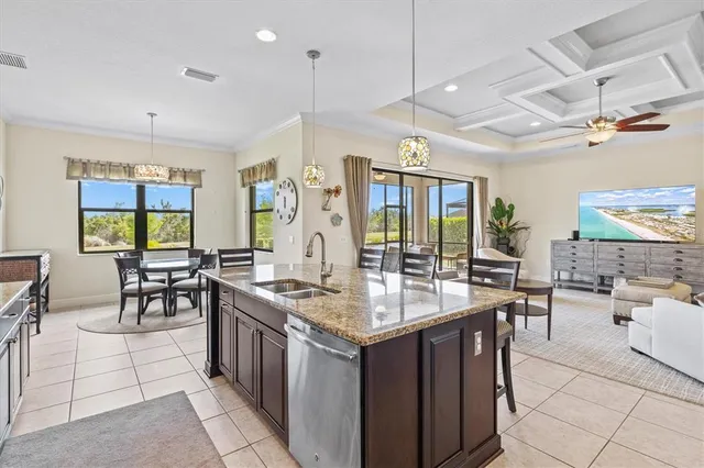 an open kitchen with stainless steel appliances granite countertop a stove a sink dishwasher and couches with wooden floor