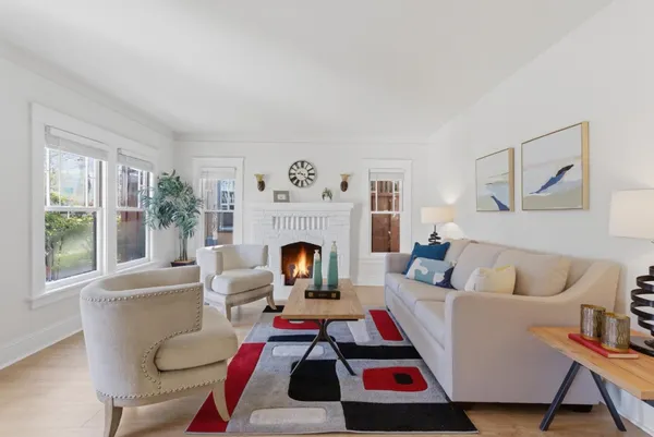 a living room with furniture a rug a fireplace and a large window