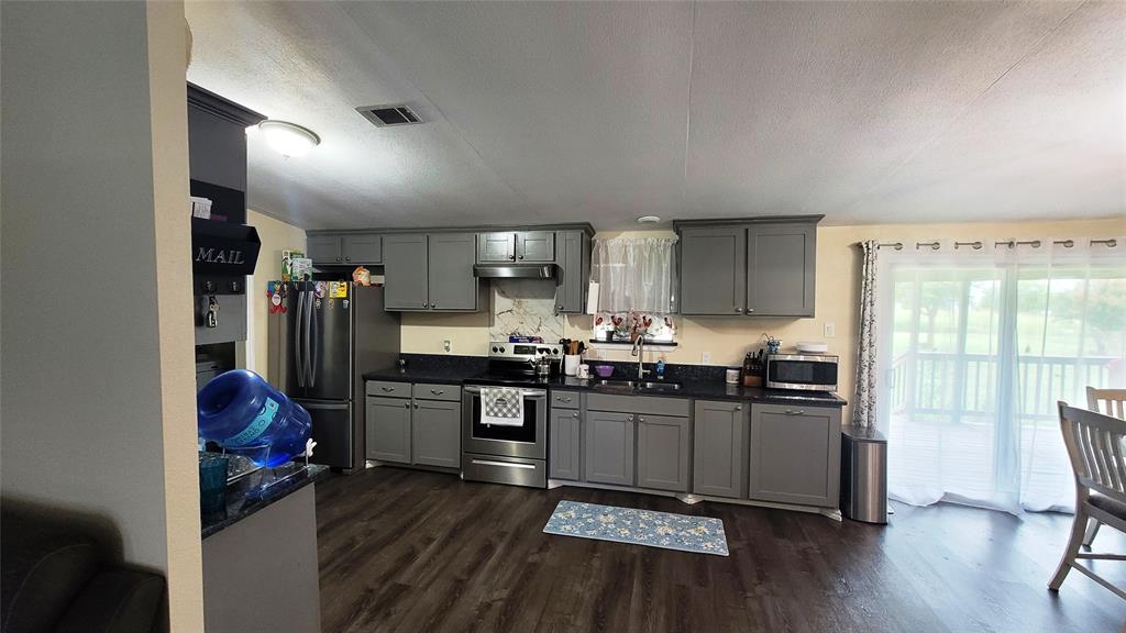 104 Mimosa Way Venus, TX 76084 - Photo 4 of 37 a kitchen with stainless steel appliances granite countertop a refrigerator a sink dishwasher a stove and white countertops with wooden floor