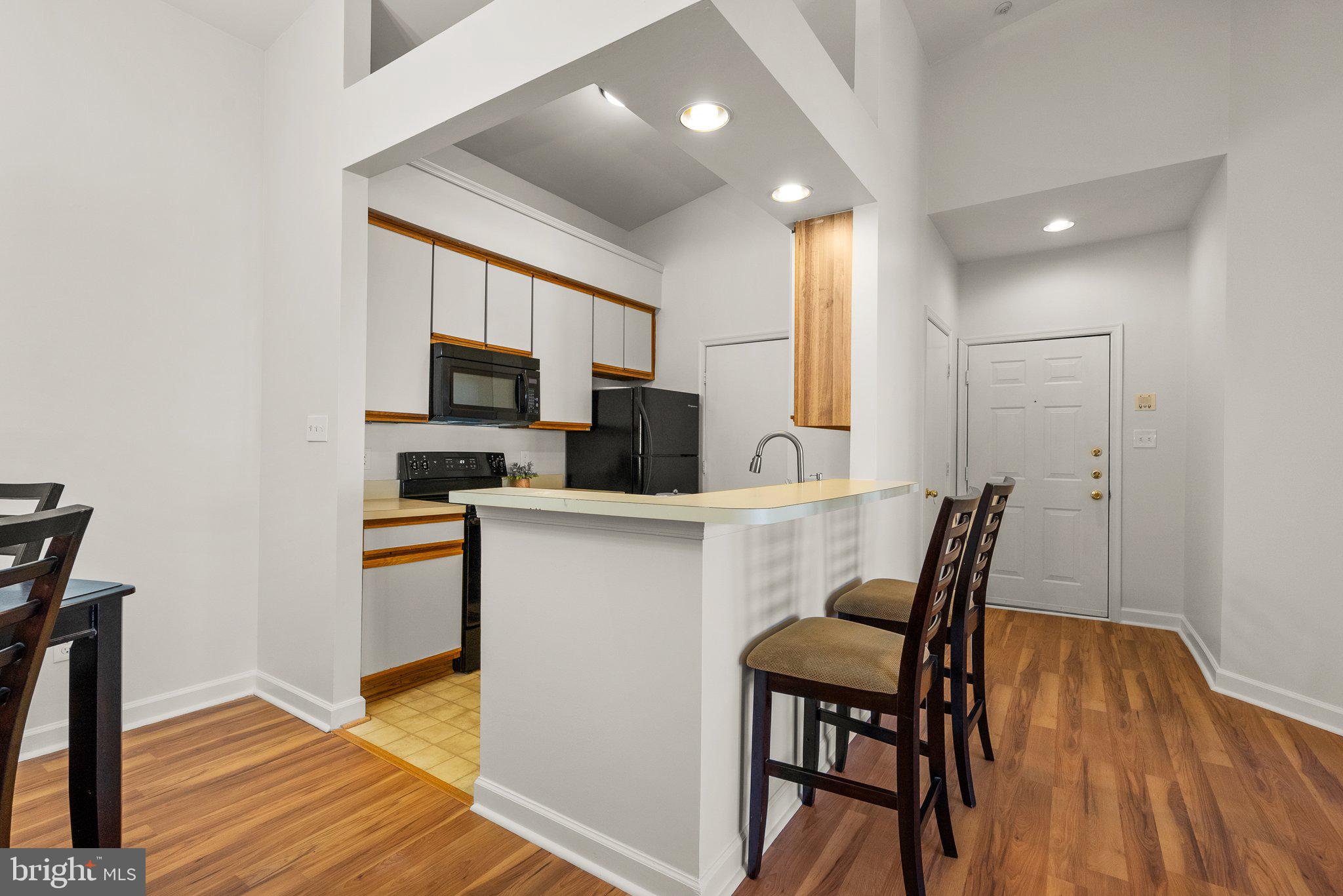 3301 Sir Thomas Drive, Unit 6B41 Silver Spring, MD 20904 - Photo 9 of 27 a kitchen with a table chairs refrigerator and microwave