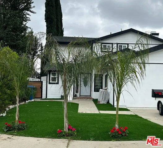 a view of a white house with a yard and potted plants