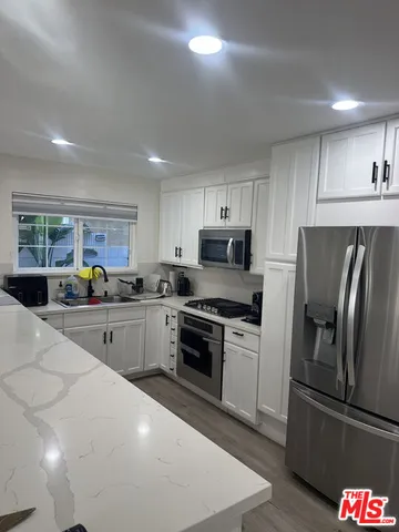 a kitchen with granite countertop a refrigerator stove and sink