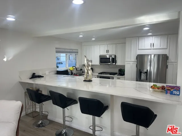 a kitchen with stainless steel appliances a dining table chairs refrigerator and sink