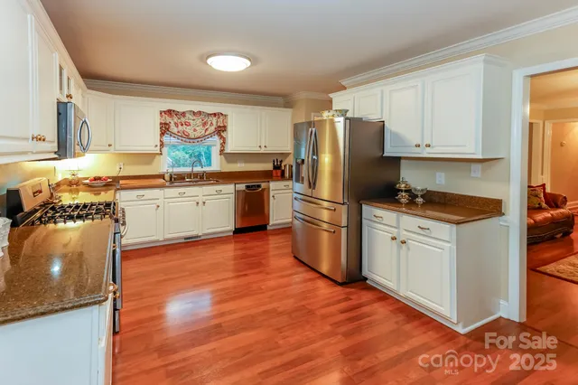 a kitchen with granite countertop a refrigerator stove top oven and sink