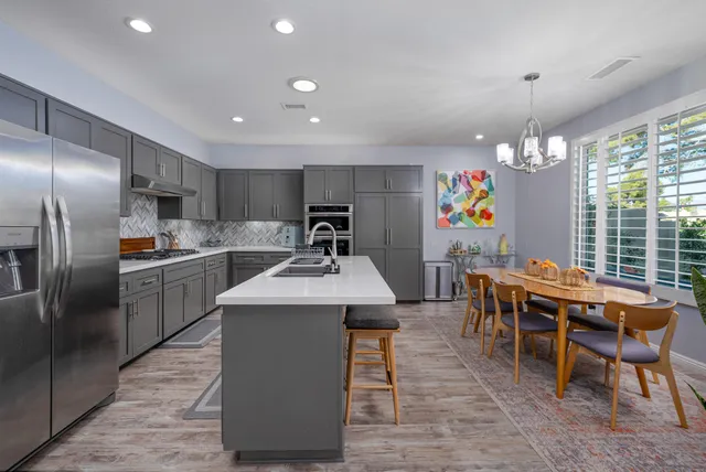 a kitchen with stainless steel appliances granite countertop a table chairs sink refrigerator and microwave