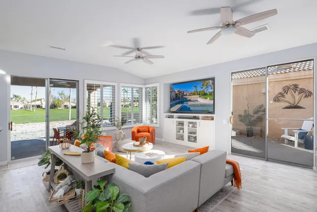 a living room with furniture floor to ceiling window and a flat screen tv