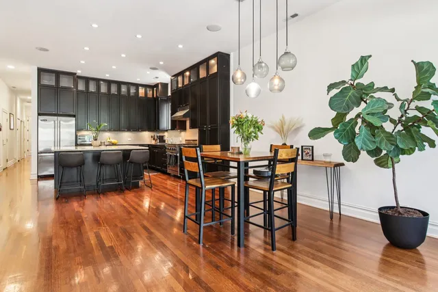 a living room with furniture a potted plant and kitchen view