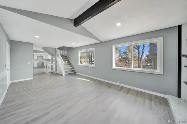 a view of an empty room with wooden floor and fireplace