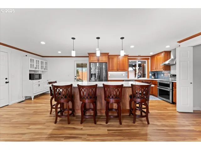 a large kitchen with a dining table chairs and white appliances