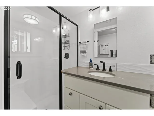 a bathroom with a granite countertop sink a mirror a vanity and shower
