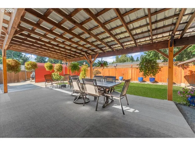 a view of a patio with table and chairs under an umbrella with a big yard