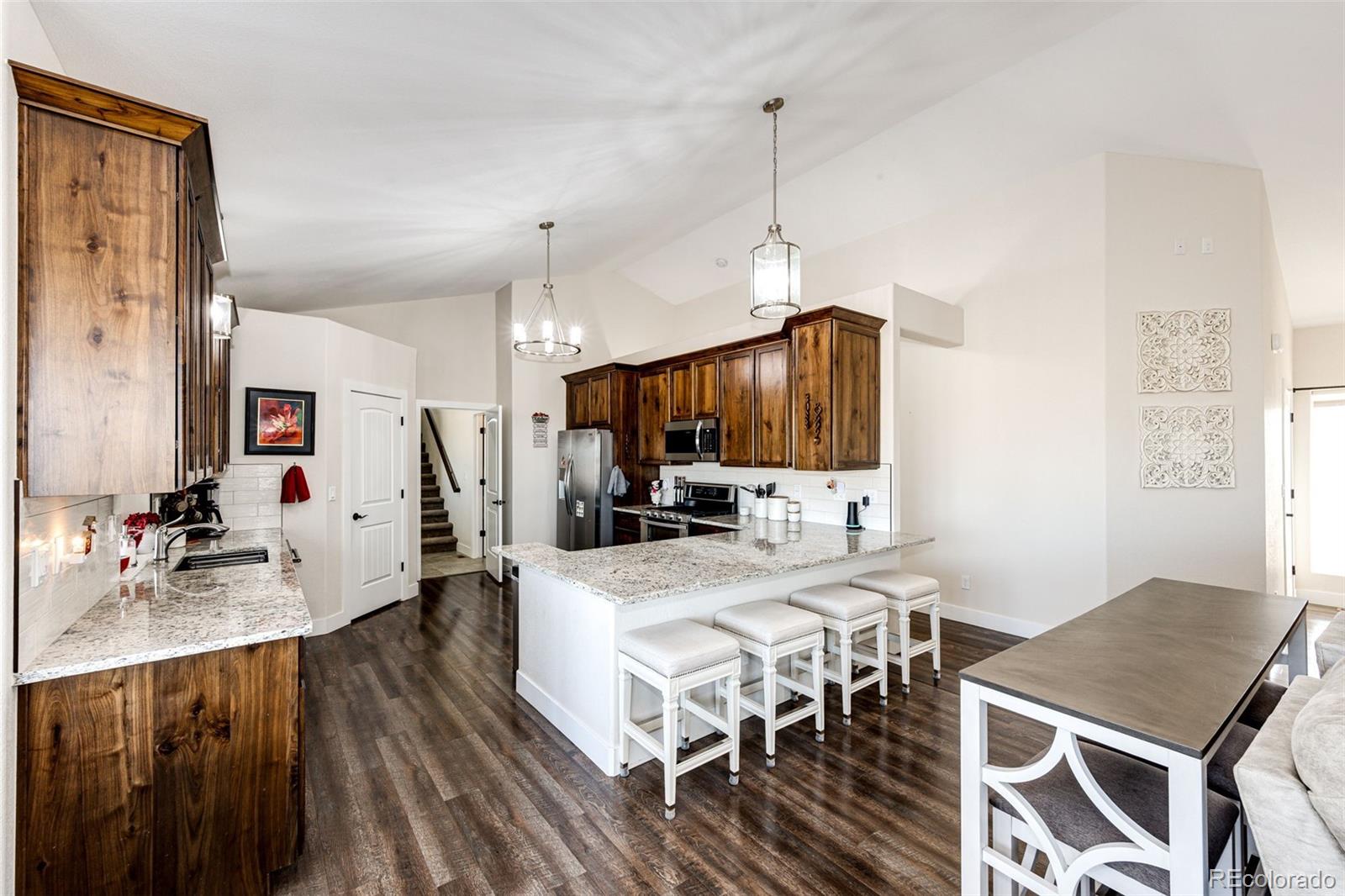 4820 Kiowa-Bennett Road Bennett, CO 80102 - Photo 12 of 29 a view of a dining room and livingroom with furniture wooden floor a chandelier
