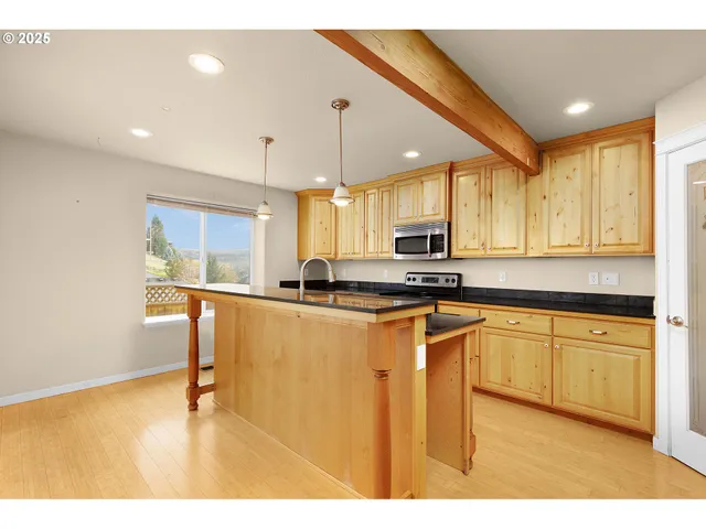 a kitchen with stainless steel appliances granite countertop a sink a stove a refrigerator cabinets and a dining table