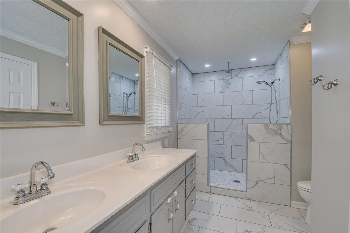 165 Morris Road Thomson, GA 30824 - Photo 5 of 26 Primary ensuite bathroom is updated with double-sink vanity, gorgeous tile shower and floors, and walk-in closet.