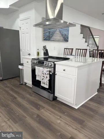a kitchen with a stove top oven cabinets and a wooden floor