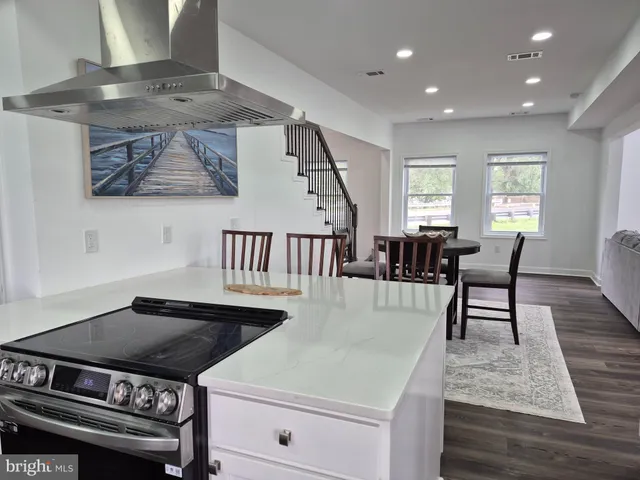 a kitchen with a stove and a dining table with wooden floor