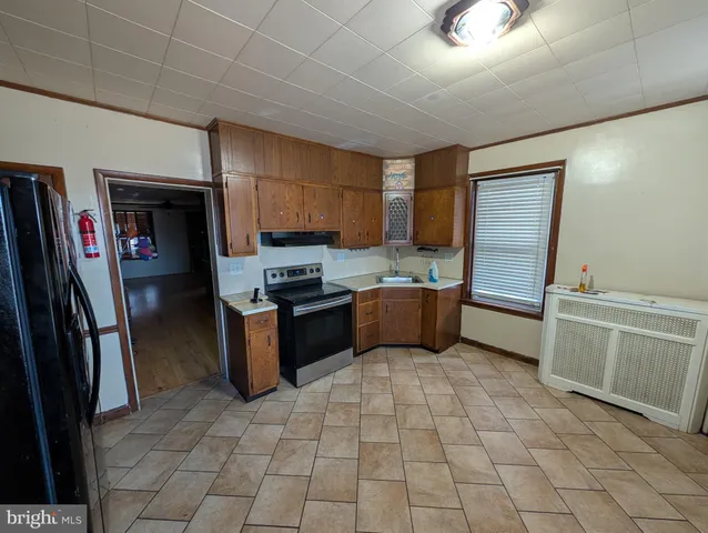 a kitchen with granite countertop a refrigerator a sink a stove top oven and cabinets