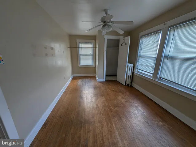 an empty room with wooden floor closet and windows