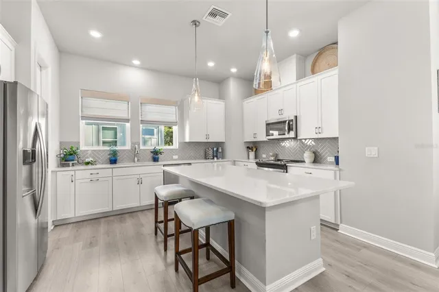 a large kitchen with granite countertop a stove a sink a refrigerator and a refrigerator