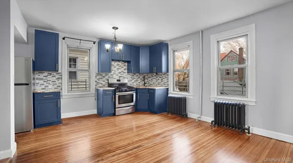 a kitchen with stainless steel appliances kitchen island granite countertop a refrigerator and a wooden floors