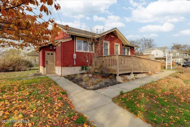 a view of a white house next to a yard with large trees