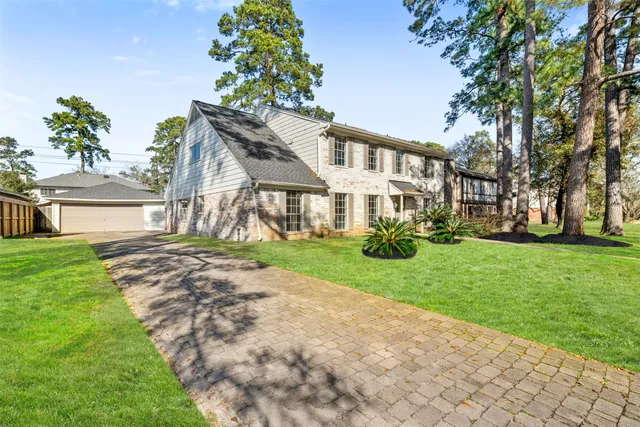 a front view of a house with a garden and trees
