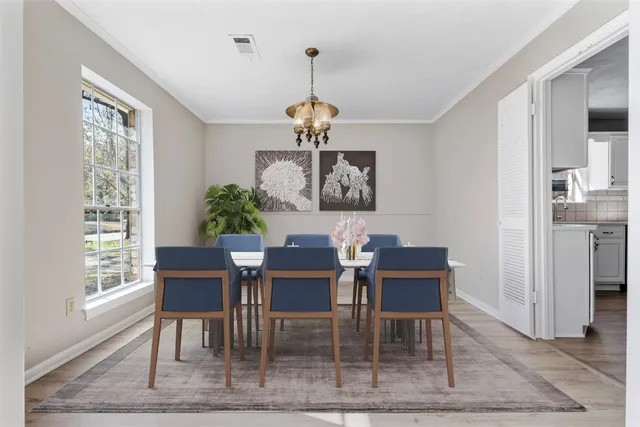 a dining room with wooden floor a chandelier a wooden table and chairs
