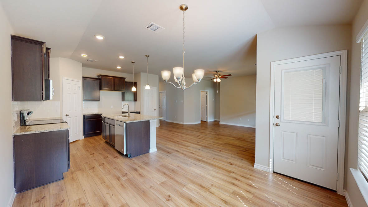 429 Creekfall Road Burnet, TX 78611 - Photo 8 of 28 A streamlined kitchen layout flows into the main living area, featuring rich wood flooring and a contemporary chandelier.