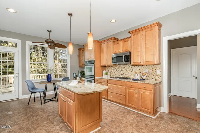 a large kitchen with kitchen island a sink a stove a dining table and chairs