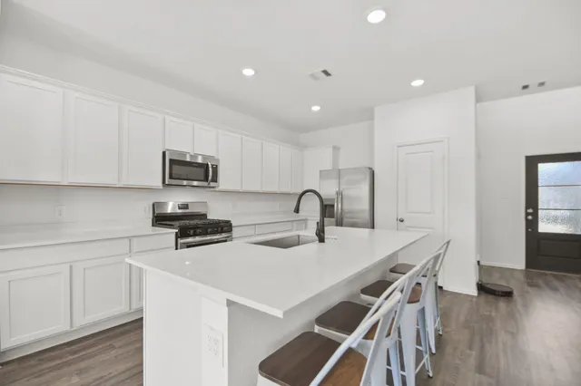 a kitchen with stainless steel appliances a stove a sink a microwave a refrigerator and cabinets