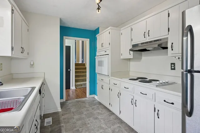 a kitchen with white cabinets and appliances
