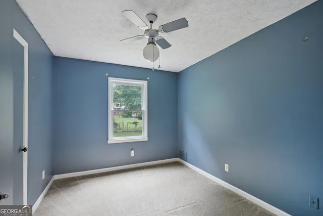 an empty room with a window and a fan