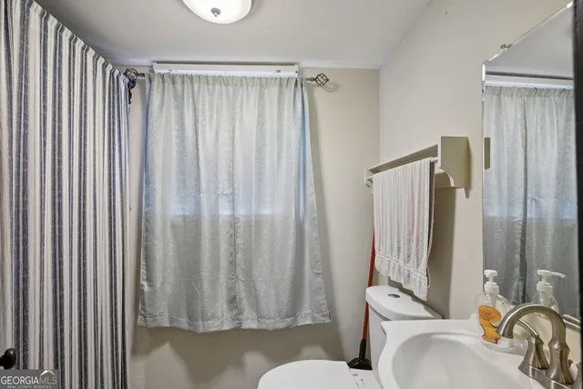 a bathroom with a sink a toilet and shower curtain