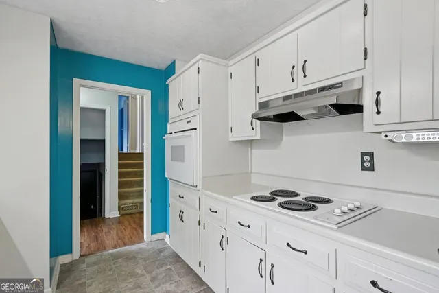 a kitchen with white cabinets and appliances