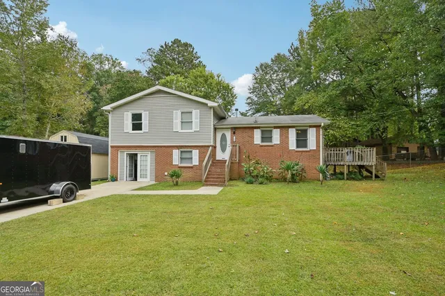a view of a house with a yard and large trees
