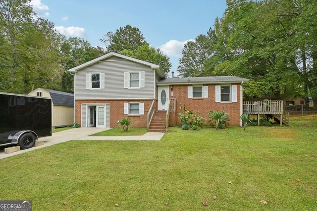 a front view of house with yard and trees in the background