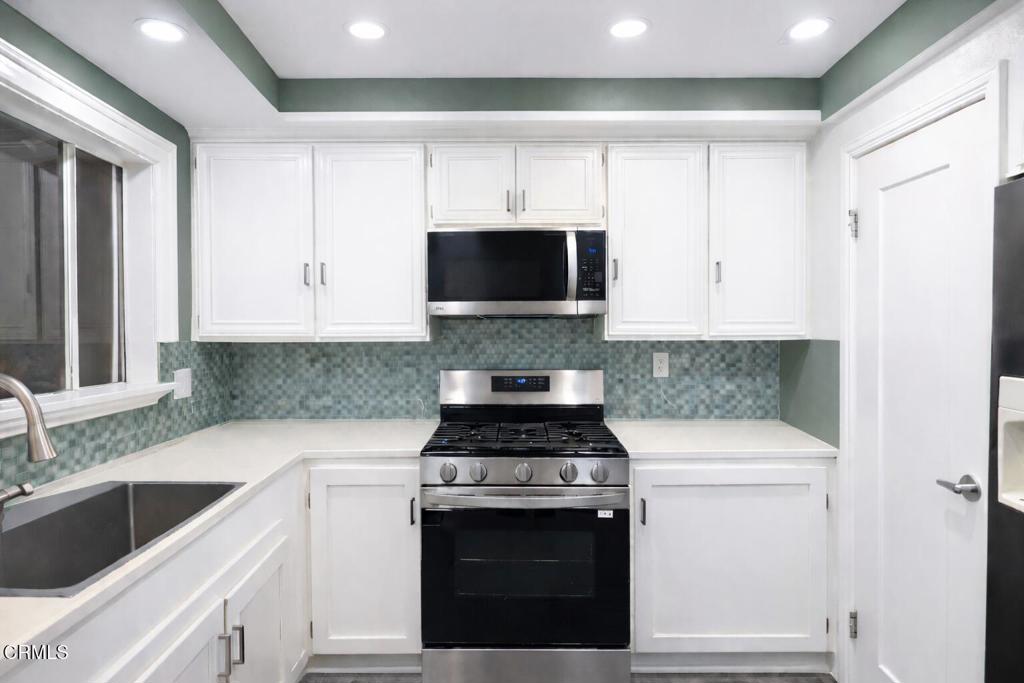 1440 Nelson Place Oxnard, CA 93033 - Photo 3 of 7 a kitchen with granite countertop white cabinets and white stove