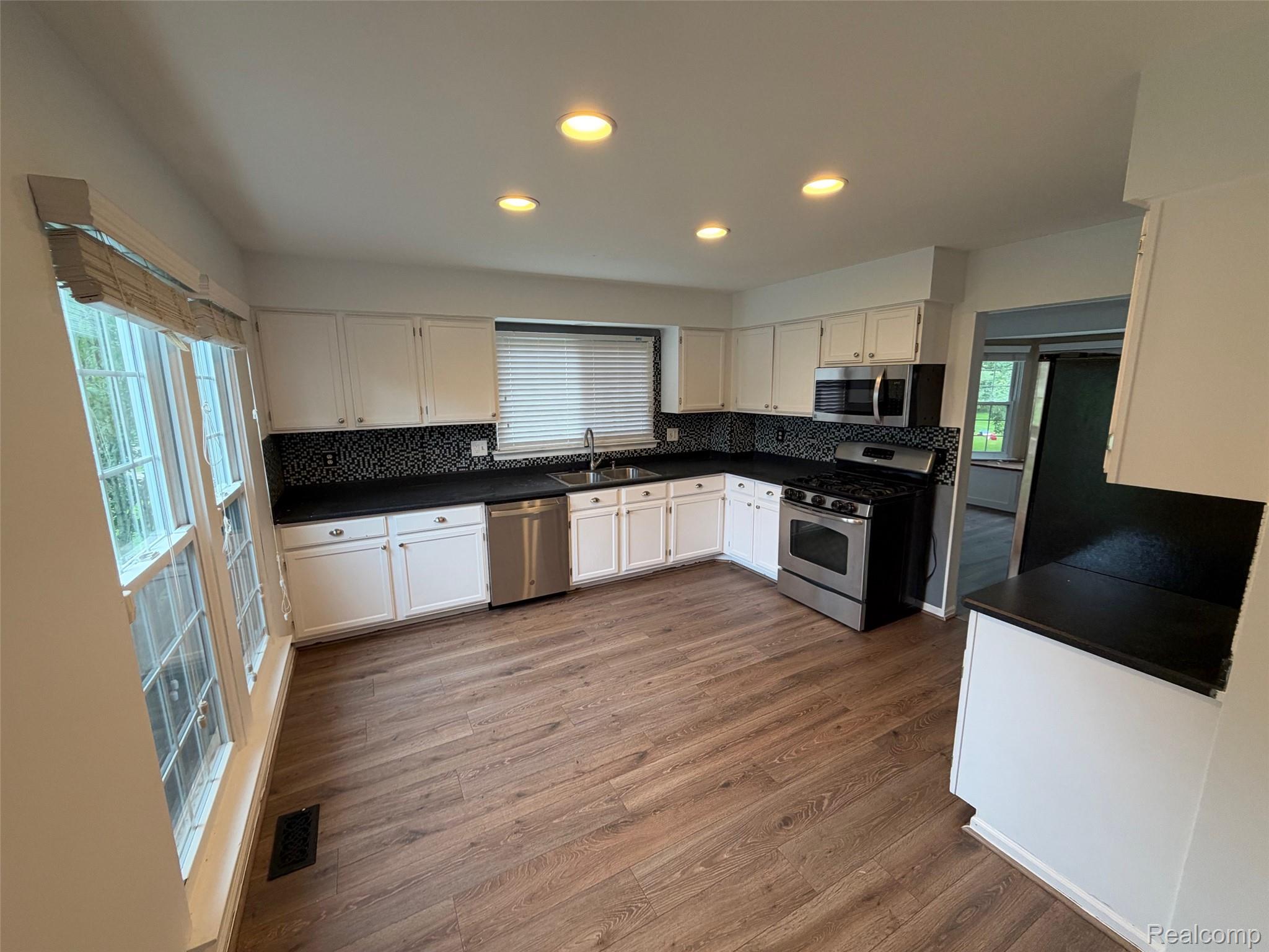 24525 Jamestowne Road Novi, MI 48375 - Photo 3 of 20 Kitchen featuring wood-finish flooring, white cabinetry, dark countertops, and a mosaic tile backsplash