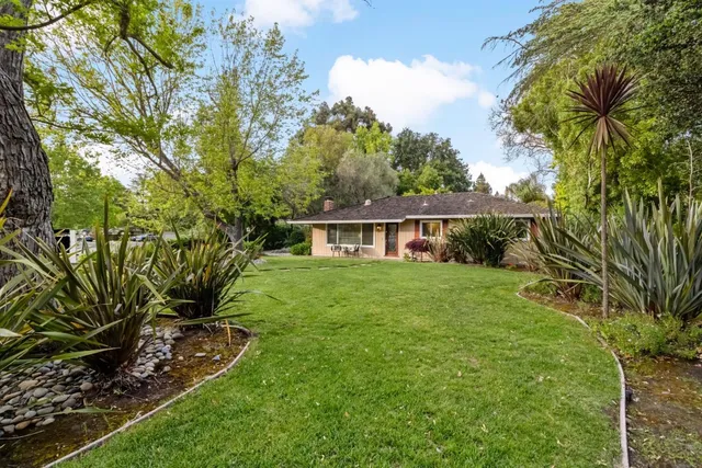 a view of a house with a big yard plants and large trees