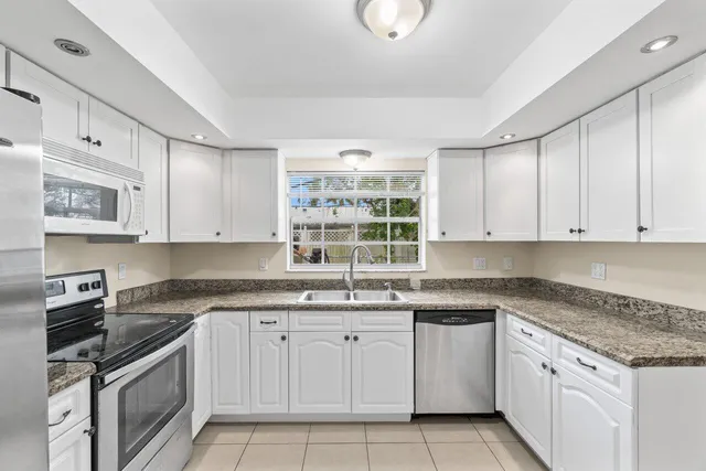 a kitchen with granite countertop white cabinets white stainless steel appliances with a sink and dishwasher
