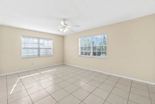 an empty room with windows and fan