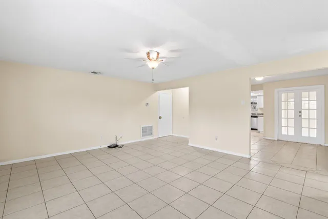 an empty room with chandelier fan and windows